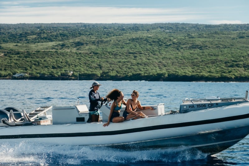 Hawaii Boat Tours: A trio of women cruise near shore off the coast of Hawaii.