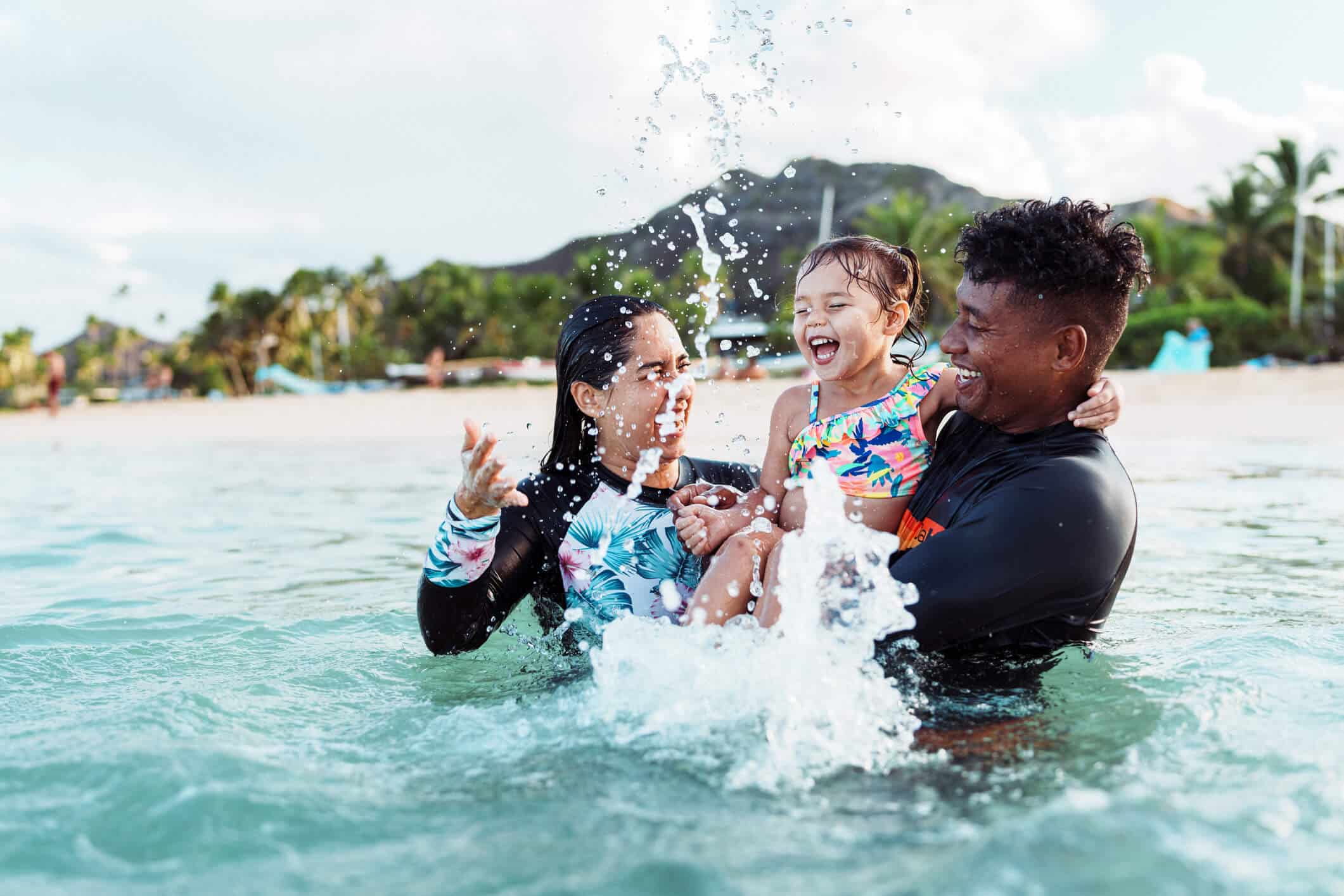 Best Family Beaches in Hawaii for Calm Water Swimming: Parents are playing with their toddler in the beach water